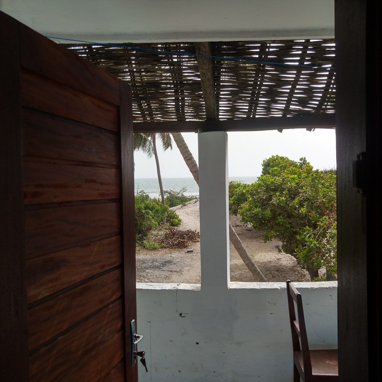  Entrée d'une chambre au Campement Buhanor, offrant une vue directe sur la végétation luxuriante et le chemin menant à la plage de Cap-Skirring.
