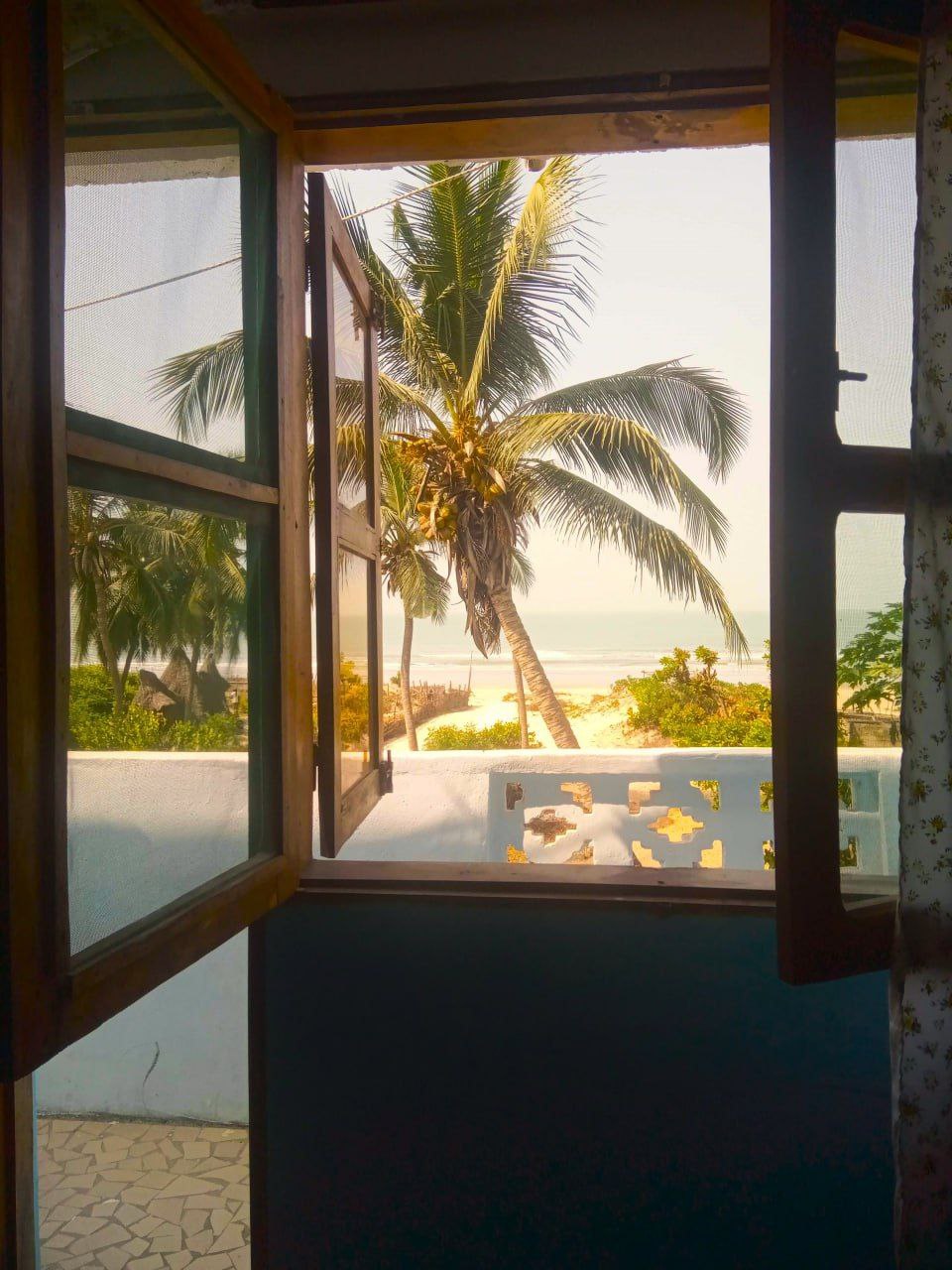 Vue imprenable sur la plage de Cap-Skirring depuis le balcon d'une chambre premium du Campement Buhanor, avec palmiers et océan.