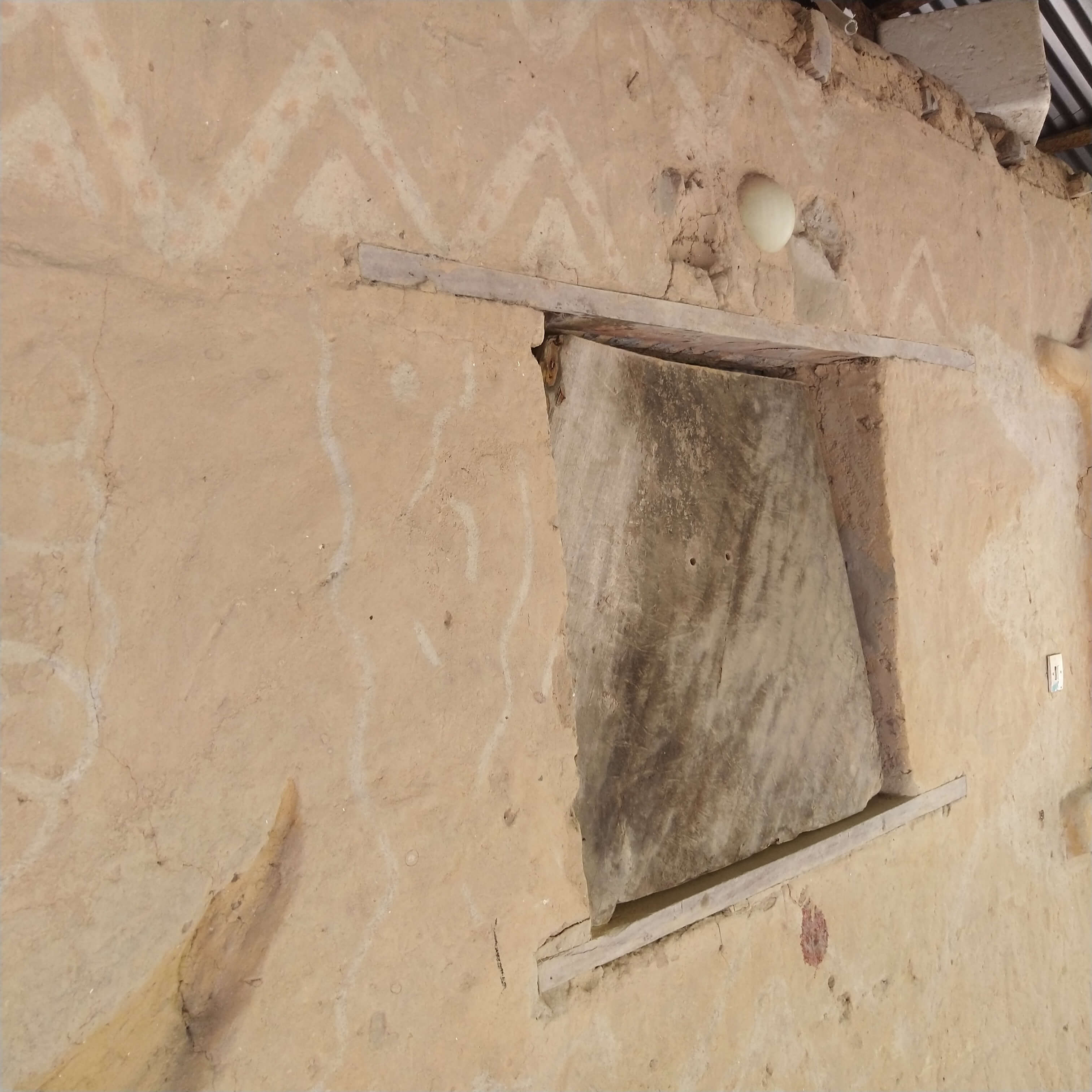 Détail architectural d'un mur en terre avec des motifs géométriques en zigzag, reflétant l'art et les techniques de construction traditionnelles de la Casamance, visible au Campement Buhanor.