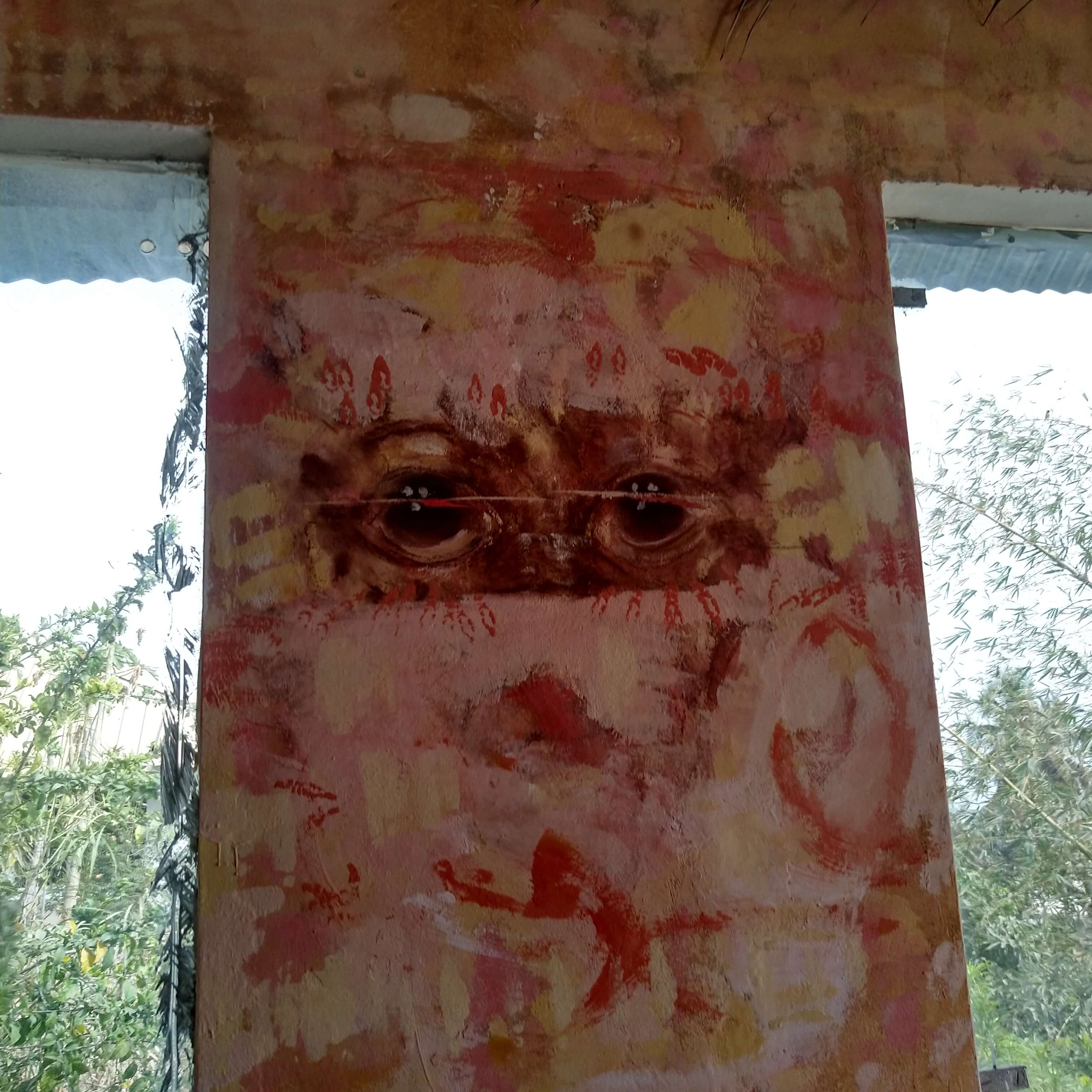 Gros plan sur une surface murale ou une sculpture avec des yeux stylisés, reflétant l'art et les motifs traditionnels de la culture Diola, intégrés dans le décor du Campement Buhanor à Cap-Skirring.