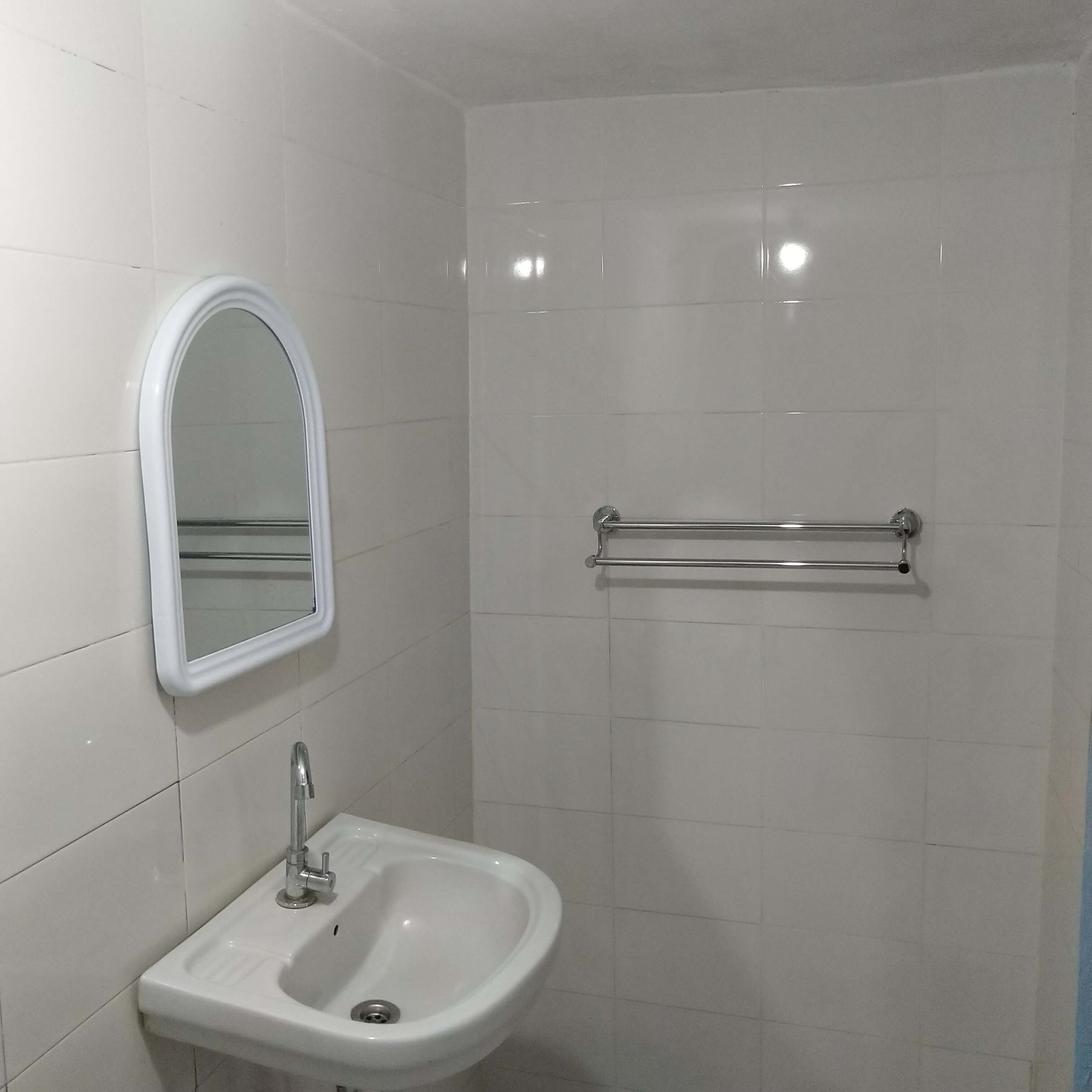  Salle de bain propre et lumineuse au Campement Buhanor, avec lavabo, miroir et porte-serviettes, assurant confort et hygiène à Cap-Skirring. 